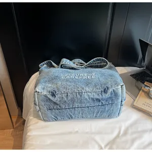 Nahaufnahme der hellblauen Denim-Tragetasche mit Stickerei und stilvollen Alltags-Accessoires