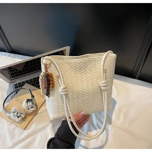 Makroansicht der gewebten cremefarbenen PU-Tasche mit stilvollem Perlenanhänger