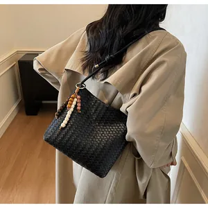 Detail einer schwarzen geflochtenen Ledertasche mit bunten Perlen am Schulterriemen