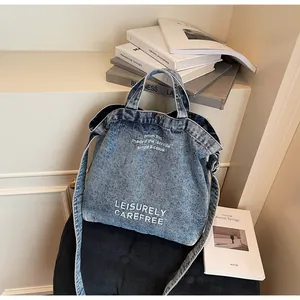 Detailansicht der Denim-Tragetasche mit weißem Aufdruck und abnehmbarem Schultergurt