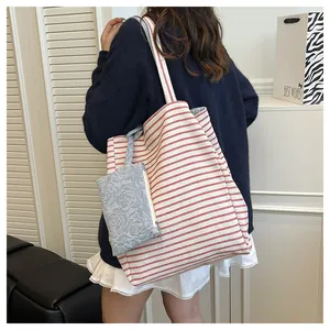 Detalle del bolso tote de lona a rayas rojas con estuche de jacquard floral azul
