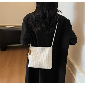 Detail einer weißen gewebten Beuteltasche mit Perlenanhänger auf einem schwarzen Mantel