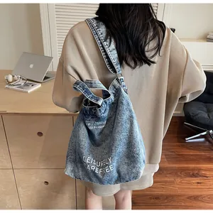 Detailansicht der blauen Denim-Einkaufstasche mit Aufdruck, von einem Model getragen