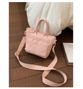 Detail of pink nylon bucket bag showing texture on brown wooden floor with books