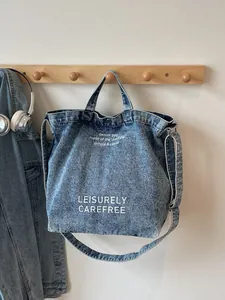 Blaue gewaschene Denim-Tragetasche mit Leisurely Carefree-Print und verstellbarem Gurt