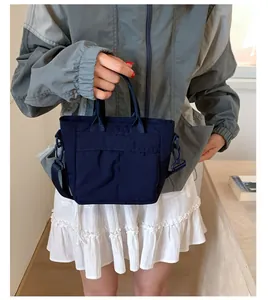 Detail of dark blue nylon bucket bag showing texture, front pocket and adjustable strap