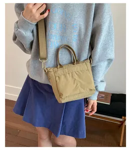 Detail of khaki nylon mini tote bag with wide canvas strap and functional front pockets