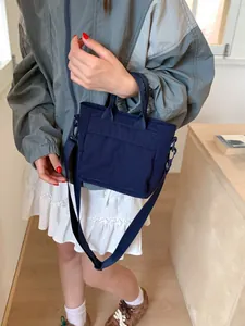 Navy blue nylon bucket bag with dual front pockets and adjustable strap shown on model