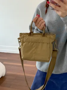 Women's khaki nylon bucket bag with dual front pockets and adjustable crossbody strap
