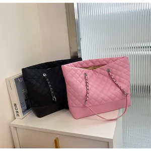 Detail view of large quilted tote bags in black and pink with chain straps and smooth texture