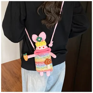 Details einer handgefertigten rosa Häkeltasche mit Regenbogenstreifen und Pilzanhänger