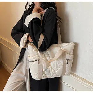 Detail of quilted tote bag with side zipper pocket and beige nylon fabric texture