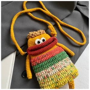 Détail du sac bandoulière tricoté main avec design de monstre aux grands yeux et lèvres rouges