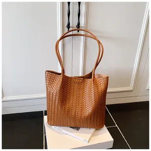 Detail of caramel leather woven tote bag showing the Intrecciato pattern and texture