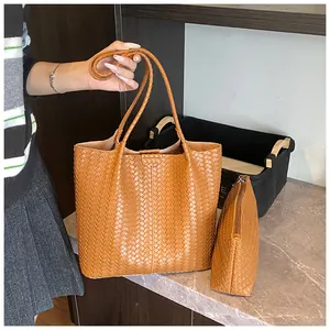 Detail view of woven brown tote bag set featuring small zippered clutch and twin handles
