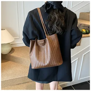 Detail of a brown woven tote bag showing the fine Intrecciato texture and matte finish