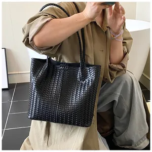 Detail of black woven leather tote bag with Intrecciato texture and long shoulder straps