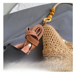 Detail of woven tote bag with adjustable brown leather strap and colorful bead accents