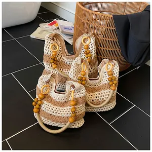 Close-up of three hollow knit tote bags with wooden bead handles and floral crochet patterns
