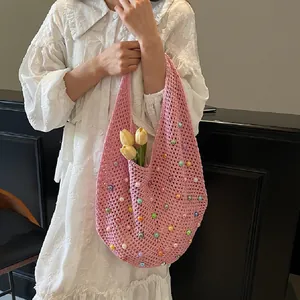 Detailed close-up of pink hollow knit tote bag with colorful beads and flower decor