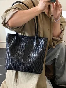 Classic black woven leather tote bag for women shown with a stylish autumn trench coat
