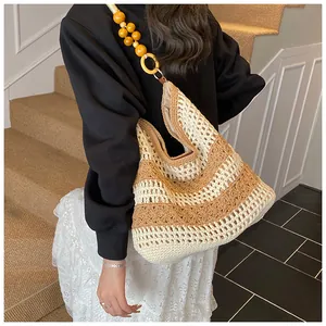 Detail of hollow-out woven tote bag with yellow bead strap and striped knit texture