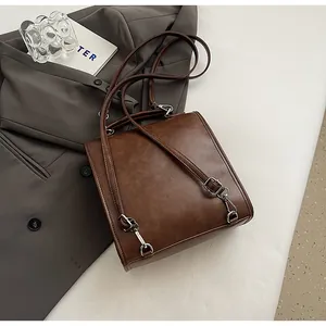 Flat lay of vintage brown PU leather backpack with silver hardware on a grey blazer