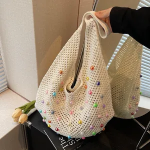 Close-up of knit hobo tote bag with colorful acrylic pearls and openwork mesh texture