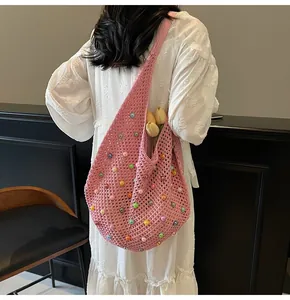Detailed close-up of pink knit shoulder bag with colorful beads on a model