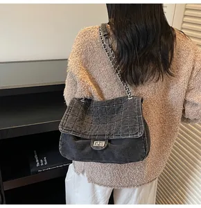 Detail of grey washed denim bag with quilted stitching and silver metal twist lock