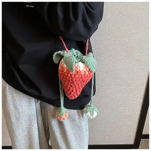 Detail of handcrafted crochet strawberry crossbody bag with miniature pendants and leaf deco