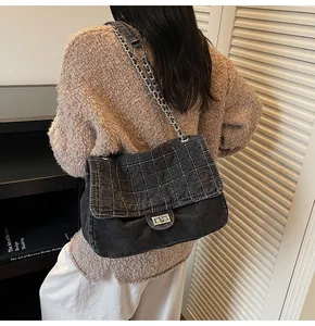 Detail of washed denim shoulder bag with white quilted stitching and silver chain strap