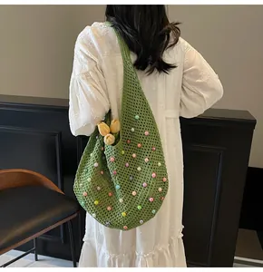 Close-up of green crochet tote bag with colorful pearl beads and hollow knit texture