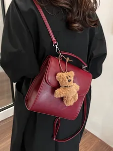 Retro deep red leather backpack with a plush bear charm worn by a model