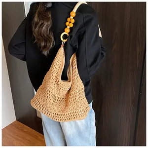 Detail of hollow out woven tote bag featuring orange wooden bead strap for beach holidays
