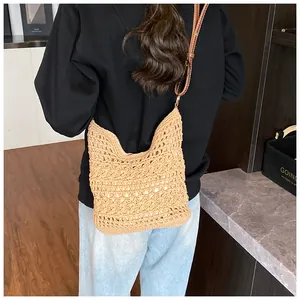 Detail of hollow woven knit tote bag with brown leather strap worn by a model