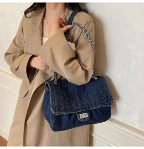 Detail of blue denim shoulder bag featuring quilted pattern and silver turn-lock closure
