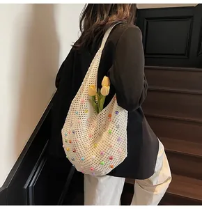 Detailed close-up of a white crochet tote bag with colorful pearl beads and floral accents