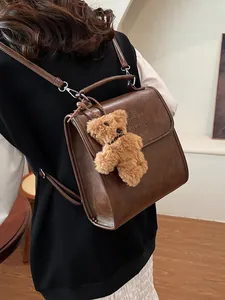 Retro brown PU leather backpack for women featuring a plush bear charm and handle