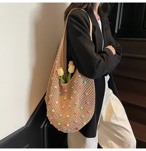 Detailed view of woven straw tote bag with colorful beads on a shoulder-carried model