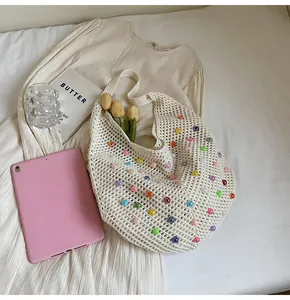 Detailed macro of a crochet tote bag with colorful beads on a beige fabric background