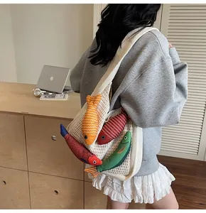 Detail of white knit shoulder bag featuring four colorful 3D plush fish ornaments