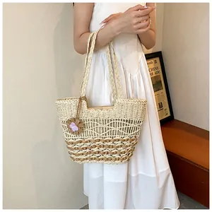 Dettaglio della borsa in paglia intrecciata a mano con design traforato e ciondolo a fiore