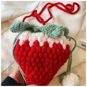 Detailed view of handmade crochet strawberry crossbody bag with green leaf and drawstrings