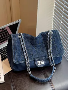 Blue denim tote bag with quilted stitching and metal chain strap on a desk