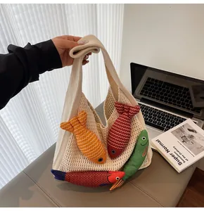 Detail of white knit tote bag with colorful 3D fish charms and thick woven texture