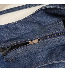 Detailed macro view of high-quality metal zipper and blue denim fabric texture on the bag