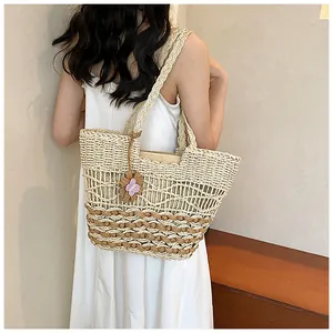 Vista dettagliata della borsa tote in paglia intrecciata con strisce marroni e ciondolo a fiore