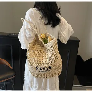 Vista detallada de un bolso de paja trenzada con estampado PARIS llevado por una modelo