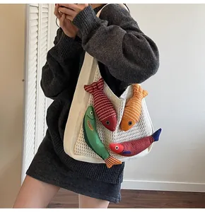 Close-up of white knitted tote bag with colorful small fish plush charms and textured fabric